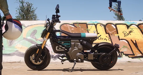 BMW CE 02 electric scooter posed in front of colorful graffiti walls in an urban setting.