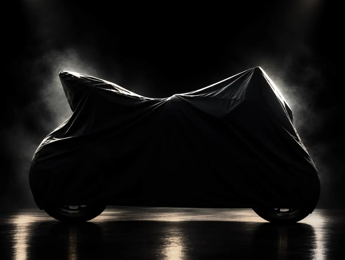 Motorcycle under a fitted black dust cover in a dark, softly lit studio setting.